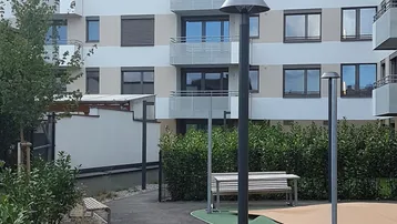 Moderne Wohnanlage mit mehreren Balkonen, begrüntem Außenbereich und Sitzgelegenheiten.
