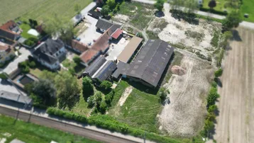 Luftaufnahme eines Anwesens mit mehreren Gebäuden, umgeben von Feldern und angrenzend an Bahngleise.