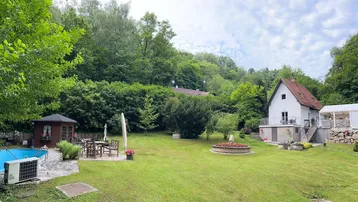 Großer Garten mit Pool, Gartenlaube und Sitzbereich, umgeben von viel Grün und Bäumen.