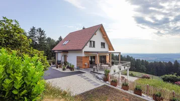 Modernes Einfamilienhaus mit Satteldach, großer Terrasse und weitem Blick über die Landschaft.
