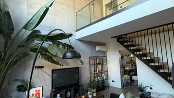 Helles, offenes Wohnzimmer im Loft-Stil mit hohen Decken, Holzdecke und Galeriebereich.