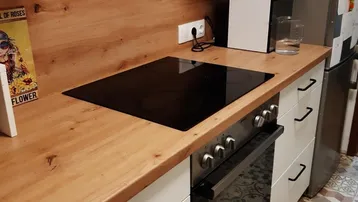Moderne Küche mit Holzarbeitsplatte, Induktionskochfeld und integriertem Backofen.