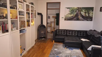 Gemütliches Wohnzimmer mit Holzboden, Kaminofen und einem großen Ecksofa.