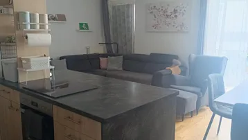 Heller offener Wohnbereich mit integrierter Küche, Sofa und Essbereich, ideal für geselliges Beisammensein.