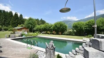 Großer Außenpool mit Holzdeck, Außendusche und malerischem Bergblick.