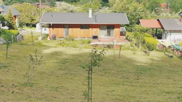 Weitläufige Ansicht des Hauses mit Holzfassade und Naturteich in ländlicher Umgebung.