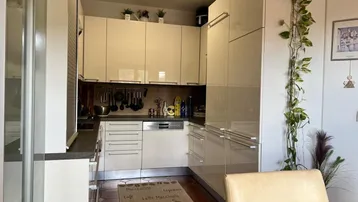 Moderne Küche mit glänzenden cremefarbenen Schränken und integrierten Geräten, gut beleuchtet.