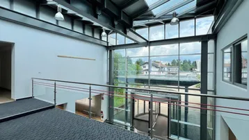 Geräumige, lichtdurchflutete Lobby mit hohen Decken, Glasfassade und Blick ins Grüne.