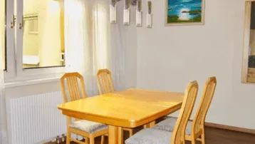 Gemütlicher Essbereich mit einem Holztisch, passenden Stühlen und viel natürlichem Licht durch das Fenster.