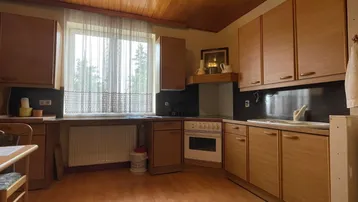 Küche im traditionellen Stil mit Holzschränken, Holzdecke und einem Fenster über der Spüle.