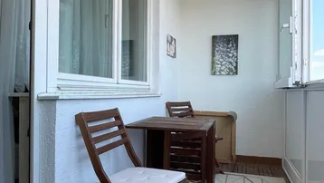 Gemütlicher Balkon mit Holzboden und Sitzgelegenheiten, ideal für entspannte Stunden im Freien.