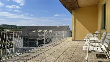 Große Sonnenterrasse mit Sitzgelegenheiten und einem weiten Blick in die umliegende Landschaft.