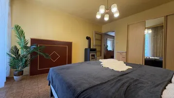 Schlafzimmer mit Doppelbett, Kaminofen und gelben Wänden, sorgt für gemütliche Wärme.