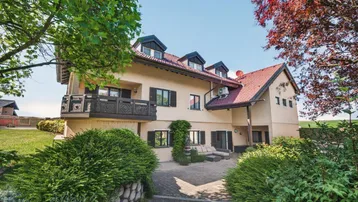 Großzügiges Einfamilienhaus mit traditioneller Architektur, Balkon und einer gemütlichen Terrasse im Grünen.