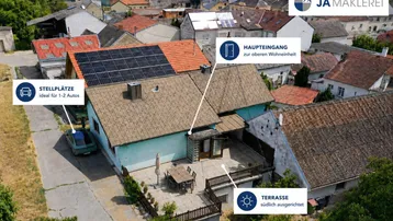 Luftaufnahme des Anwesens mit Haus, südlich ausgerichteter Terrasse, Stellplätzen und Solaranlage auf dem Dach.