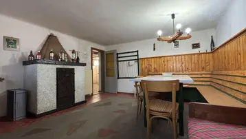 Gemütlicher Essbereich mit Kachelofen, Holzvertäfelung und rustikalen Möbeln.