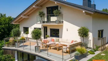 Große, möblierte Terrasse mit Glasgeländer und Pflanzen, darunter ein Balkon mit Bergblick.