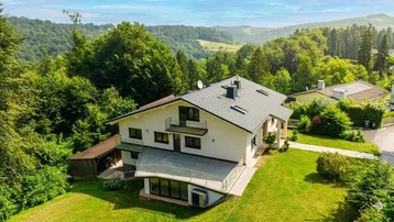 Modernes Einfamilienhaus mit großzügiger Terrasse und grüner Umgebung aus der Vogelperspektive.