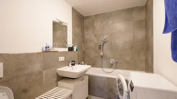 Modernes Badezimmer mit Badewanne, Waschbecken und Waschmaschine.