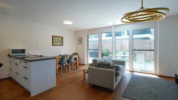 Heller Wohn-Essbereich mit Holzboden, Zugang zur Terrasse und integrierter Küchenzeile.