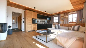Heller, offener Wohnbereich mit moderner Küche, Kamin und Holzelementen im alpinen Stil.