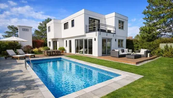 Modernes weißes Haus mit Swimmingpool, Holzterrasse und Gartenmöbeln unter blauem Himmel.