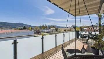 Geräumige Dachterrasse mit Holzboden, Hängesessel und weitem Blick auf die Berge und die Umgebung.