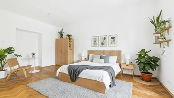 Helles Schlafzimmer mit Holzbett, Parkettboden und vielen Pflanzen für eine gemütliche Atmosphäre.