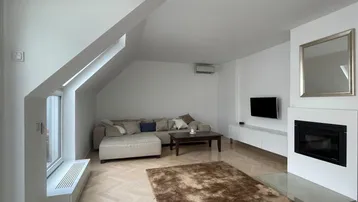 Helles Wohnzimmer mit Dachschrägen, Parkettboden, Kamin und Klimaanlage.