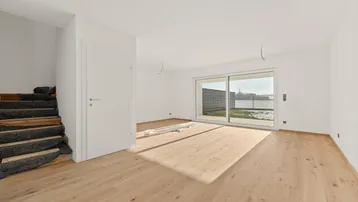 Helles, unmöbliertes Wohnzimmer mit neuem Parkettboden und Zugang zur Terrasse.