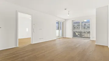Heller Wohnbereich mit Parkettboden und Zugang zu einem Balkon, ideal für entspannte Stunden.