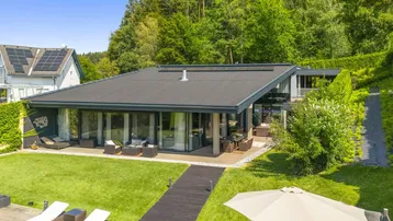 Moderne Villa mit weitläufigem Garten, großer Terrasse und Blick auf die umliegende Natur.