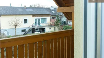 Blick vom Holzbalkon auf die umliegenden Häuser und den Gartenbereich.