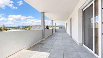 Geräumige Terrasse mit Fliesenboden und weitem Blick über die Dächer und Landschaft.