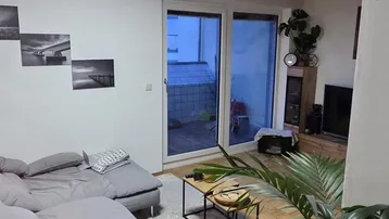 Gemütliches Wohnzimmer mit Holzdecke, Parkettboden und Zugang zur Terrasse.