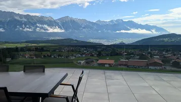 Große Terrasse mit Esstisch und Stühlen, bietet einen atemberaubenden Blick auf die Berge und das Tal.