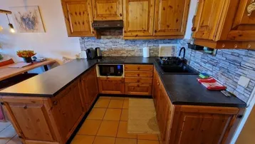 Rustikale Holzküche mit dunkler Arbeitsplatte, integrierten Geräten und gefliestem Spritzschutz.