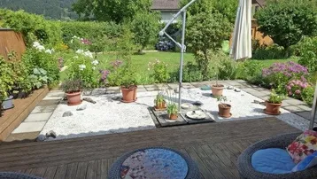 Gemütliche Terrasse mit Holzdeck, Gartenmöbeln und Blick auf den gepflegten Garten.