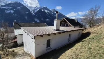 Haus mit Blechdach und beeindruckendem Bergblick in einer ländlichen Umgebung.