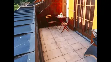 Sonniger Balkon mit Fliesenboden, Sitzgelegenheiten und weitem Blick auf die Berglandschaft.