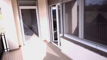 Heller Balkon mit Fliesenboden, Rollläden und Zugang zu den Innenräumen, sonnendurchflutet.