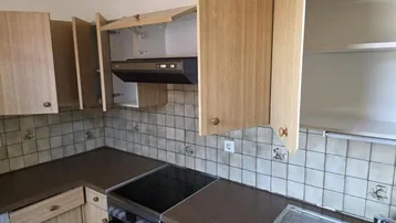 Funktionale Küche mit hellen Holzschränken, gefliestem Spritzschutz und integriertem Herd.