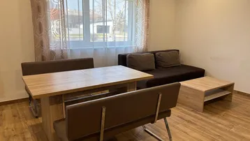 Heller Wohn- und Essbereich mit modernem Laminatboden, bequemer Couch und Esstisch.