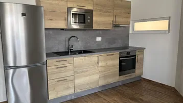 Funktionale Einbauküche mit Holzfronten, integrierten Geräten und kleinem Fenster.