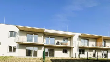 Moderne Wohnanlage mit mehreren Balkonen unter klarem blauem Himmel.