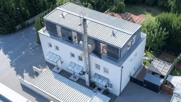 Moderne Architektur mit Flachdach und Holzverkleidung, umgeben von viel Grün.