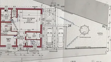 Grundriss des Erdgeschosses mit Wohn-Esszimmer, Küche und Stellplätzen.