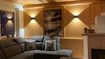 Gemütliches Wohnzimmer im alpinen Stil mit Holztäfelung, Kamin und bequemer Sitzecke.