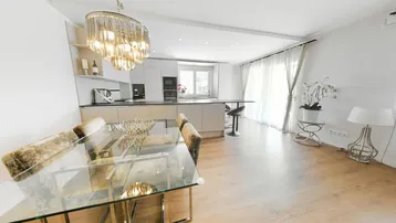 Heller offener Wohn- und Essbereich mit moderner Küche, elegantem Esstisch und Holzboden.