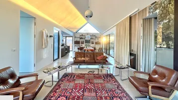 Geräumiges Wohnzimmer mit hohen Decken, großen Fenstern und gemütlichen Ledersofas.